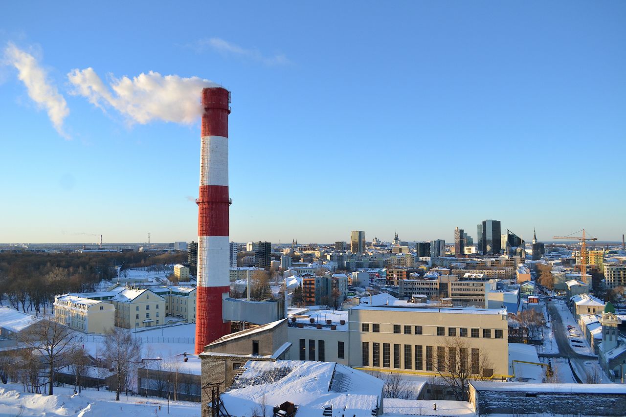 Aerial view of Tallinn in winter with snow-covered rooftops and a smoking chimney in Estonia.