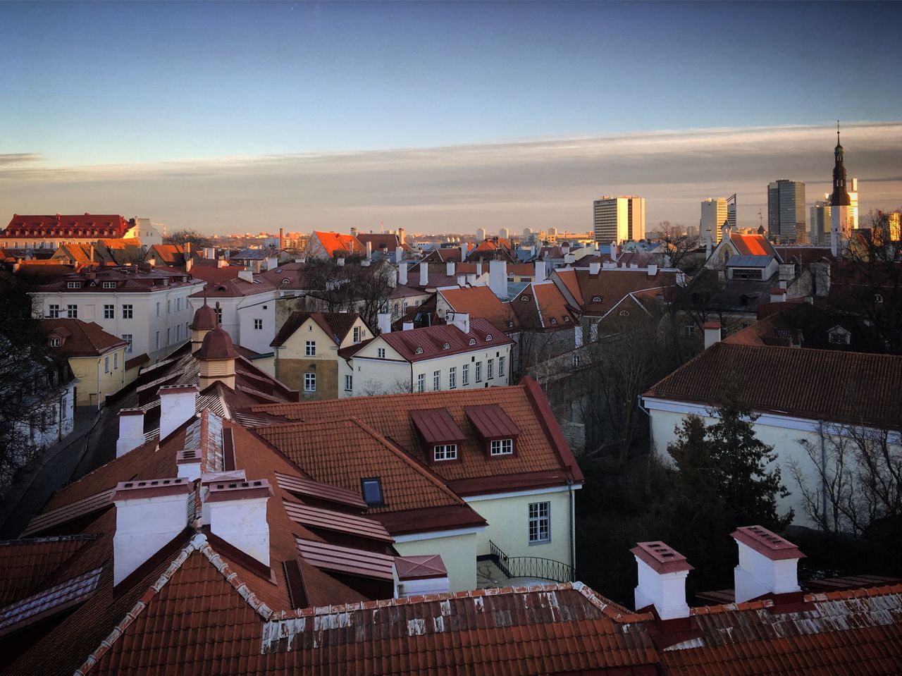 services-03 Stunning aerial view of Tallinn's Old Town with red rooftops and modern skyline at sunset.